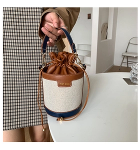 Detail of drawstring bucket bag showing contrast brown leather and cream fabric texture