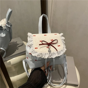 Light blue bow backpack with white lace trim and heart charm pendant on white stool