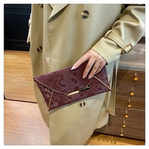Détail de la pochette enveloppe bordeaux en serpent avec bordure en métal doré chic