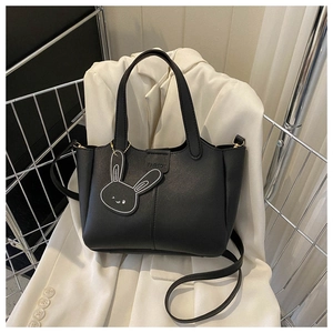 Détail du sac seau noir en cuir PU avec étiquette mode et pendentif lapin mignon
