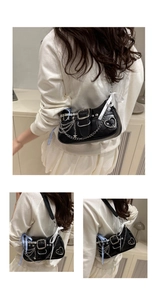 Detail of black leather underarm bag with metal chains, stars, and ribbon accents