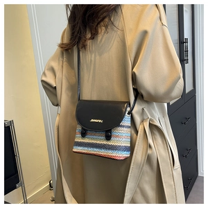 Detail of colorful woven shoulder bag featuring a black leather flap and golden metal logo