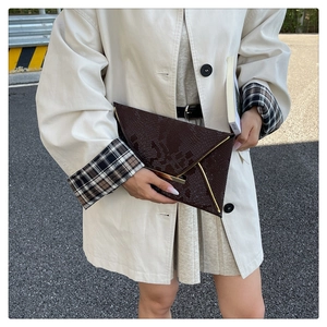Détail d'une pochette enveloppe marron foncé à motif animal et bordure dorée