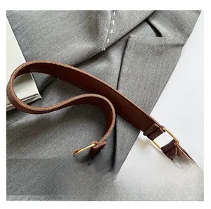 Detail of brown litchi leather texture, handle stitching, and metal hardware on handbag