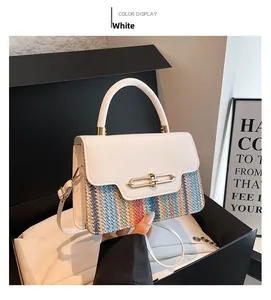 Close-up of white leather and rainbow woven texture with golden twist lock on shoulder bag