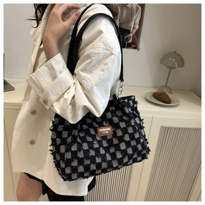 Détail du sac cabas à damier avec bords effilochés et étiquette de mode en cuir brun