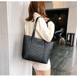 Détail d'un sac cabas en cuir noir avec surpiqûres en losanges porté par un mannequin