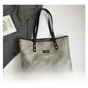 Vista piatta di borsa tote grigia tie-dye con manici neri ed etichetta moda