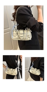 Detail of a beige faux leather underarm bag with silver chains and star heart charms