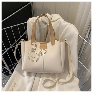 Détail du sac seau crème avec boucle kaki tendance et charmant pendentif lapin blanc