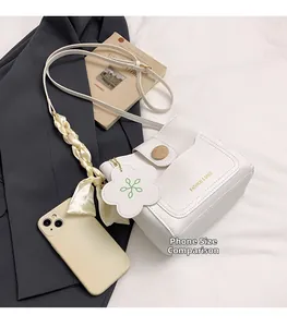 Detailed view of white bucket bag with wooden buckle and silk ribbon accessory