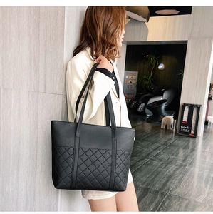 Détail d'un sac cabas en cuir noir avec surpiqûres matelassées sur la partie basse