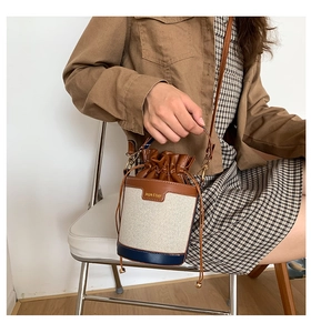 Detail of canvas bucket bag showing brown leather drawstring and contrast color design