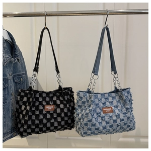 Gros plan sur des sacs cabas en denim à carreaux avec franges et chaînes en métal
