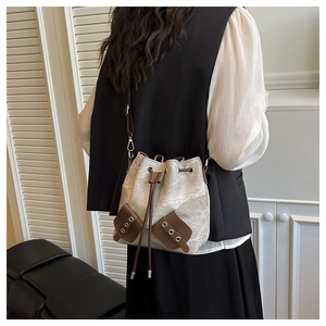 Model view of a vintage canvas and brown leather bucket bag with drawstring and strap