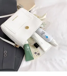Internal capacity of white leather crossbody bucket bag showing phone and cosmetics