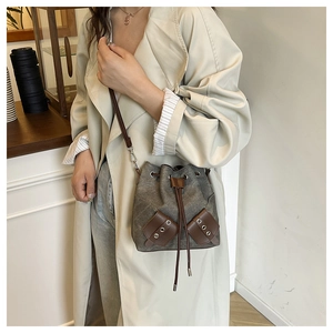 Detail of retro bucket bag showing dark green canvas texture and brown leather accents