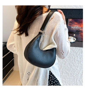 Close-up of minimalist black lychee grain crescent bag worn as a shoulder bag