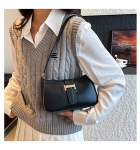 Detail der Vintage schwarzen Schultertasche mit goldener H-Schnalle an einem Model