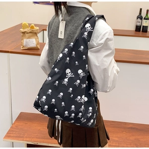 Detail van een zwarte canvas tote bag met witte schedelpatronen op de schouder