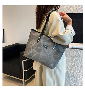 Grande borsa tote grigia con trama marmorizzata su un modello in una stanza moderna