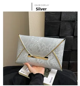 Détail de pochette enveloppe argentée avec texture serpent et bordures métalliques dorées