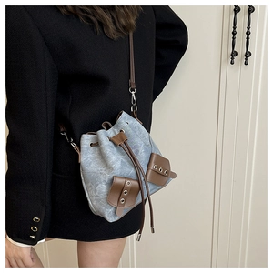 Detail of light blue bucket bag with brown leather drawstring and metal eyelets