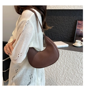 Detailed view of brown lychee leather crescent bag with adjustable shoulder strap and metal buckle
