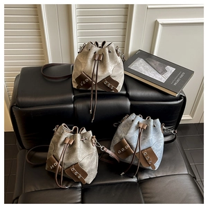 Close-up of three vintage bucket bags in beige, taupe and denim blue on a leather sofa