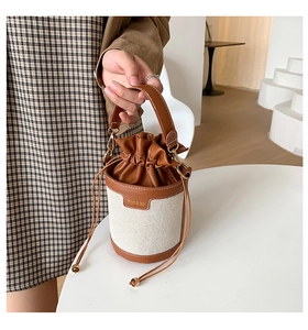 Detail of canvas bucket bag with brown leather trim and drawstring closure