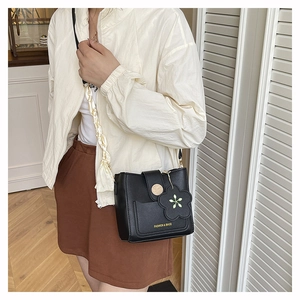 Détail du sac seau noir avec breloque fleurie, poignée en soie et texte imprimé