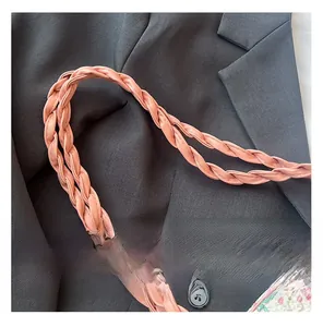 Gros plan de la poignée en cuir synthétique tressé rose avec texture détaillée du sac