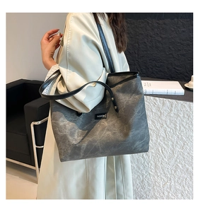 Vista laterale di una borsa tote grigia con toppa fashion indossata da una modella