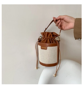 Close-up of canvas bucket bag with brown leather drawstring closure and gold hardware