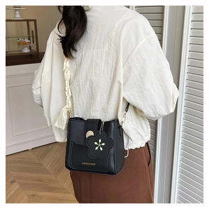 Detail of black mini bucket bag with gold lettering, floral charm and silk scarf decoration