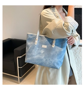 Dettaglio della borsa tote in denim azzurro con finiture in pelle bianca e borchie dorate