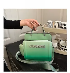 Close-up of green gradient handbag with Steve Madden logo and branded wide strap