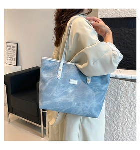 Dettaglio della borsa tote azzurra effetto marmo con logo fashion e sottili spalline