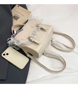 Detail of cream PU leather backpack featuring lace trim and cartoon buckle closures