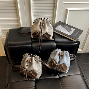 Three minimalist drawstring bucket bags in beige, green, and denim blue with leather trim