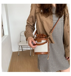 Canvas bucket bag with leather trim shown on model with shoulder strap and drawstring