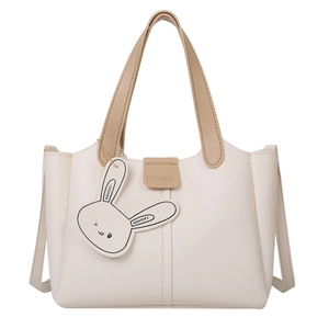 Chic beige leather bucket tote bag with brown handles and a cute bunny pendant charm