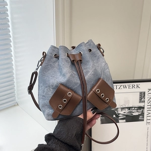 Chic vintage denim bucket bag with brown leather drawstring and shoulder strap for women