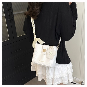 Détail du sac seau en cuir PU blanc avec ruban en soie et breloque fleur sur mannequin