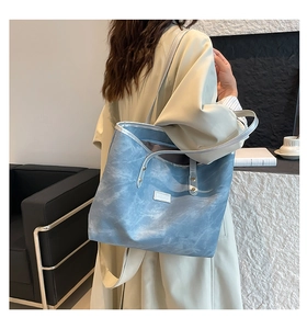 Dettaglio della borsa tote tie-dye azzurra con rivetti metallici e logo frontale