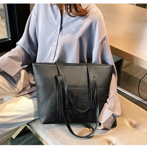 Détail d'un sac cabas noir avec motif de roses en relief et doubles anses élégantes