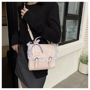 Detail of light pink Lolita crossbody bag with lace trim and decorative bows on the cover