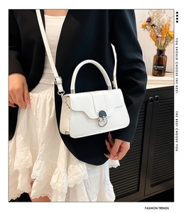 Detailed view of the white crossbody bag with elegant metal circular lock and top handle