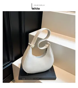 Detail shot of white crescent shoulder bag with lychee grain texture and gold hardware