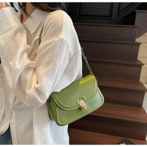 Detail of avocado green vintage flap bag with metal square lock worn by a model
